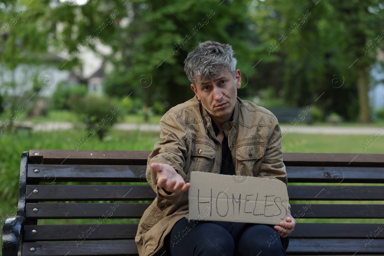Poor man with sign Homeless begging for money on bench in park Photo of Poor man with sign Homeless begging for money on bench in park