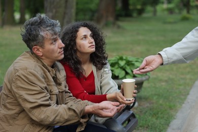 Photo of Man giving money to homeless people in park, closeup