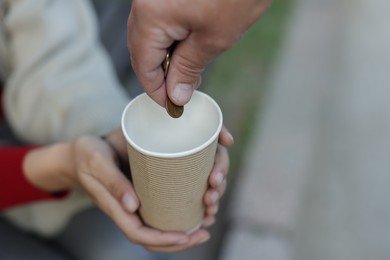 Photo of Man giving money to homeless people outdoors, closeup. Space for text