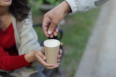Photo of Man giving money to homeless people outdoors, closeup. Space for text