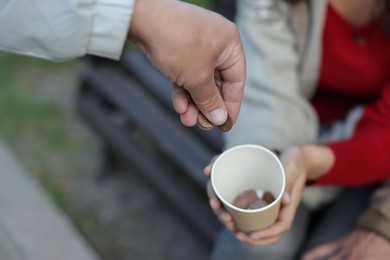Photo of Man giving money to homeless people outdoors, closeup