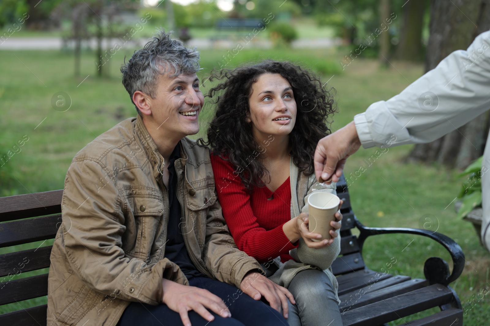 Photo of Man giving money to homeless people in park, closeup