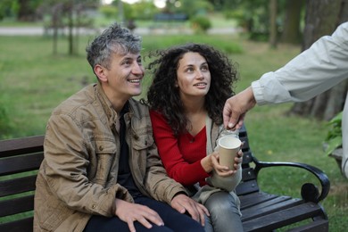 Photo of Man giving money to homeless people in park, closeup