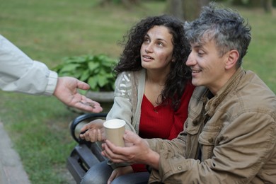 Photo of Man giving money to homeless people in park, closeup