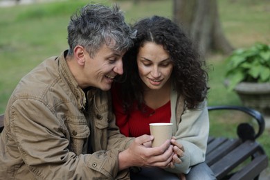 Photo of Homeless people with paper cup on bench in park