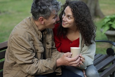 Photo of Homeless people with paper cup on bench in park