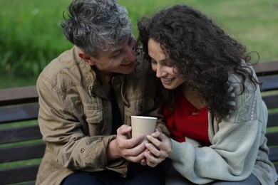 Photo of Homeless people with paper cup on bench in park