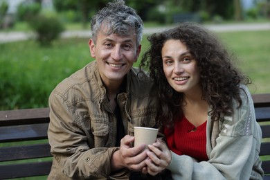Photo of Homeless people with paper cup on bench in park