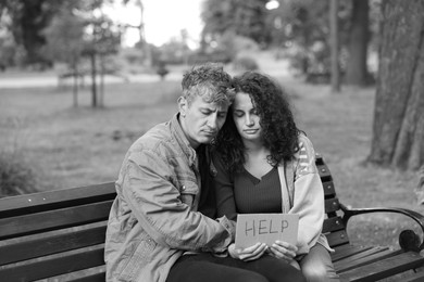 Photo of Homeless people with sign Help on bench in park. Black and white effect
