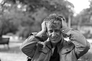 Photo of Portrait of homeless man outdoors. Black and white effect