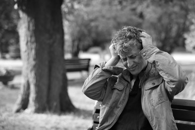 Photo of Homeless man on bench in park, space for text. Black and white effect