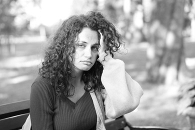 Photo of Homeless woman on bench in park, space for text. Black and white effect