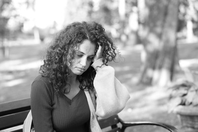 Photo of Homeless woman on bench in park, space for text. Black and white effect