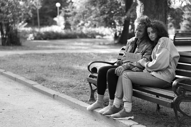 Photo of Homeless people with sign Help on bench in park, space for text. Black and white effect