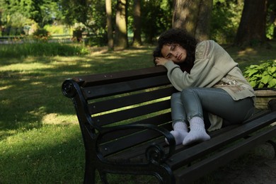 Photo of Poor homeless woman on bench in park