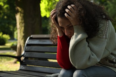 Photo of Poor homeless woman on bench in park, space for text