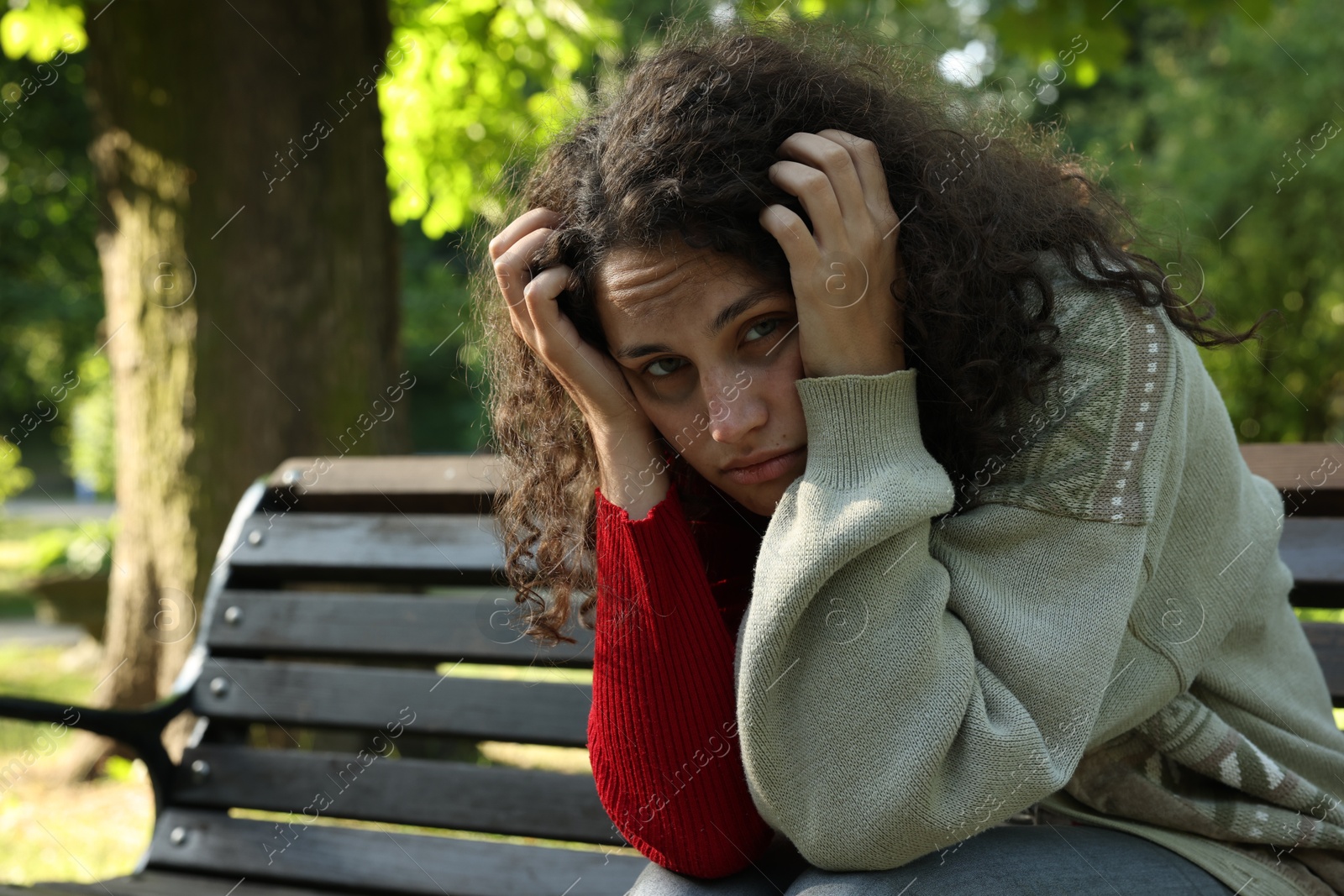 Photo of Poor homeless woman on bench in park, space for text