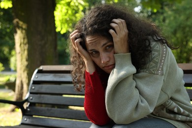Photo of Poor homeless woman on bench in park, space for text