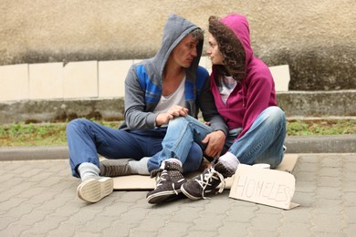 Photo of Poor people on carton and sign Homeless outdoors
