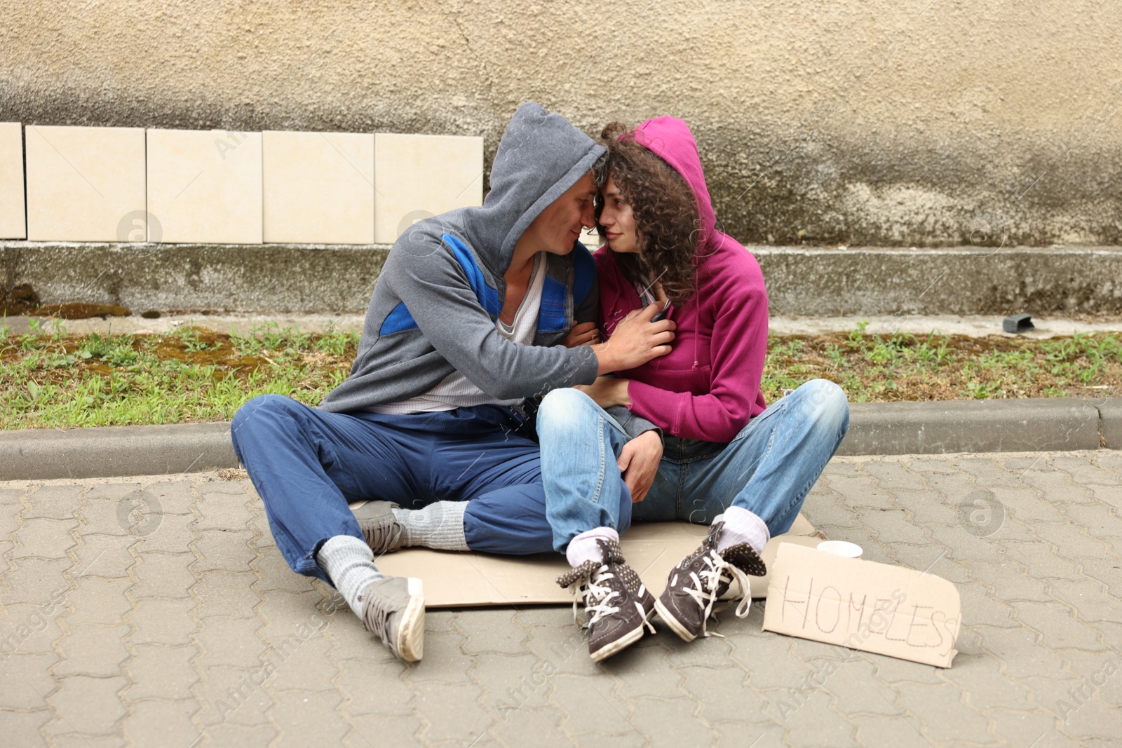 Poor people on carton and sign Homeless outdoors Photo of Poor people on carton and sign Homeless outdoors