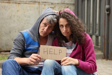 Photo of Poor homeless people with sign Help outdoors