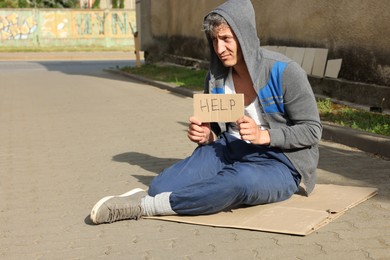 Photo of Homeless man with sign Help on carton outdoors, space for text