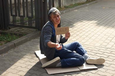 Photo of Homeless man with sign Help begging for money on carton outdoors