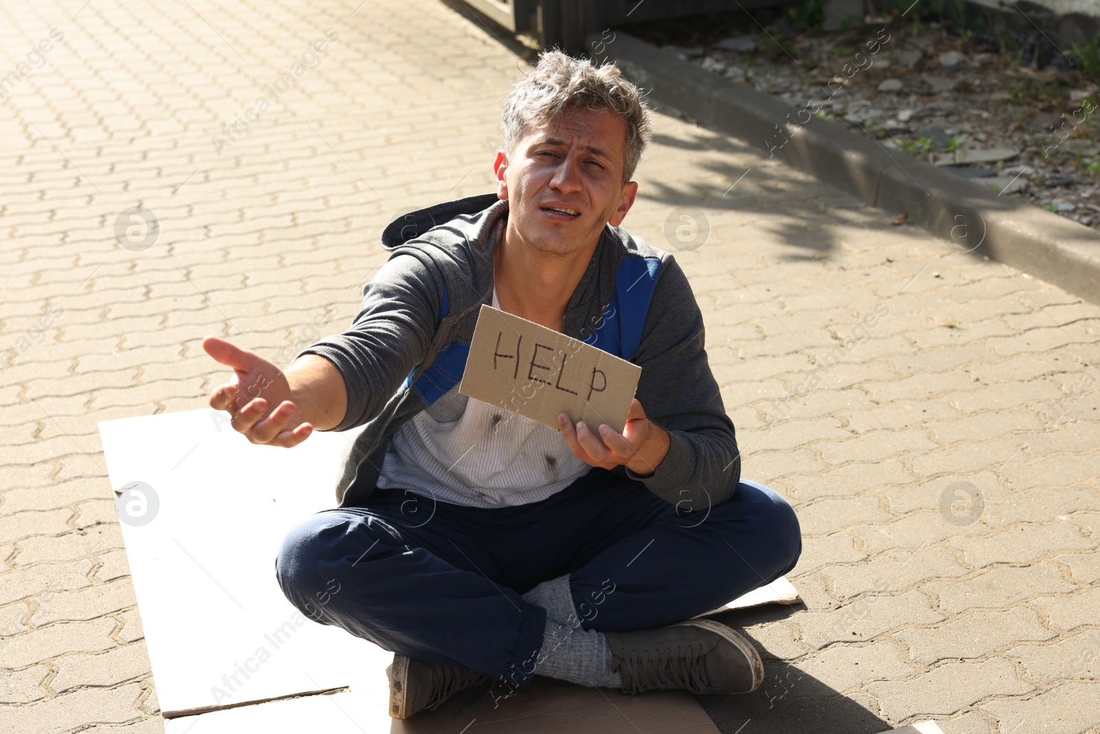 Homeless man with sign Help begging for money on carton outdoors Photo of Homeless man with sign Help begging for money on carton outdoors