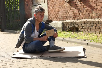 Photo of Homeless man with sign Help on carton outdoors, space for text