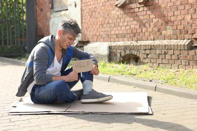 Photo of Homeless man with sign Help on carton outdoors, space for text