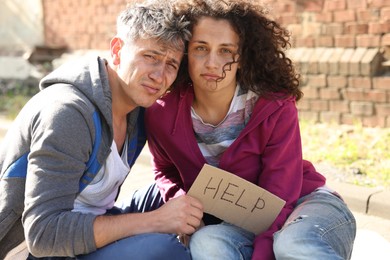 Photo of Homeless people with sign Help on city street