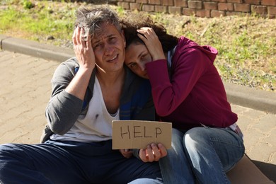 Photo of Homeless people with sign Help on city street