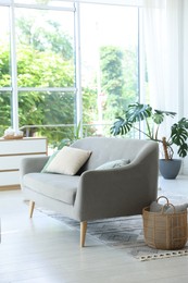 Photo of Comfortable sofa, cabinet and green houseplant indoors. Interior design