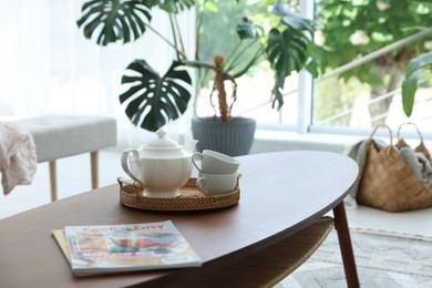 Photo of Teapot, cups and magazines on coffee table in dining room
