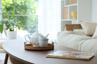 Photo of Teapot, cups and magazines on coffee table in dining room