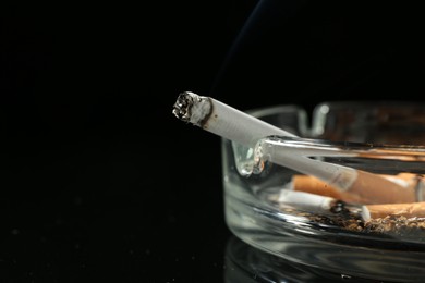 Photo of Cigarette butts in ashtray on black background, closeup. Space for text