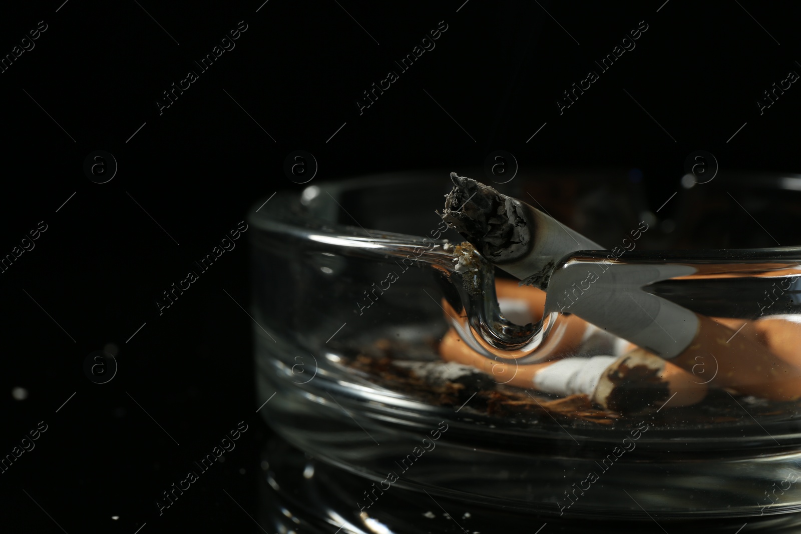 Cigarette butts in ashtray on black background, closeup Photo of Cigarette butts in ashtray on black background, closeup