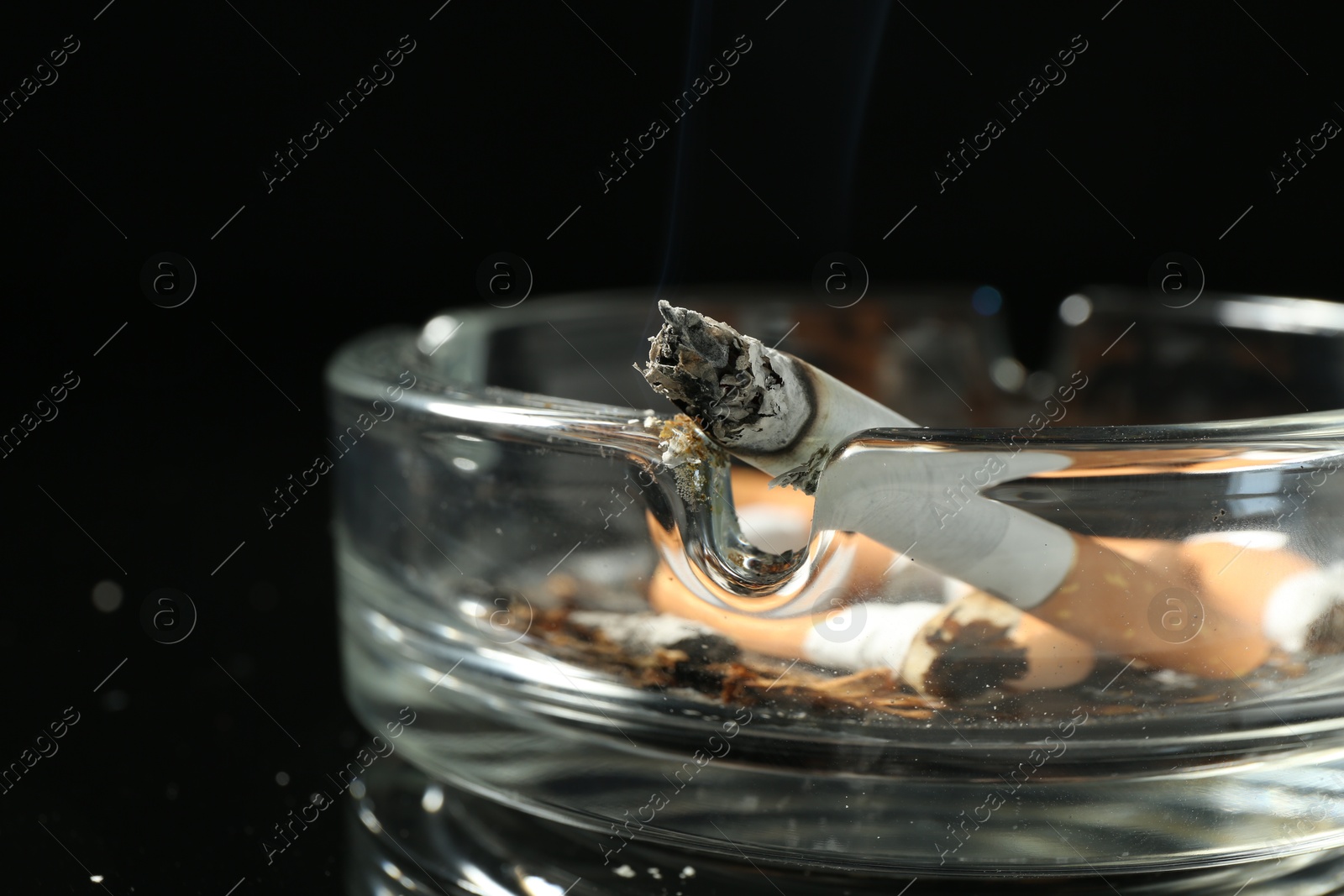 Cigarette butts in ashtray on black background, closeup Photo of Cigarette butts in ashtray on black background, closeup