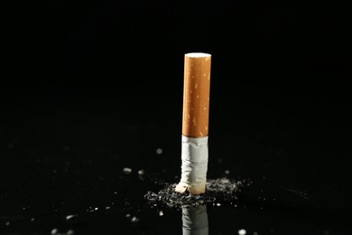 Photo of Cigarette butt with ash on black background