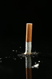 Photo of Cigarette butt with ash on black background