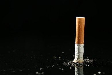 Photo of Cigarette butt with ash on black background. Space for text