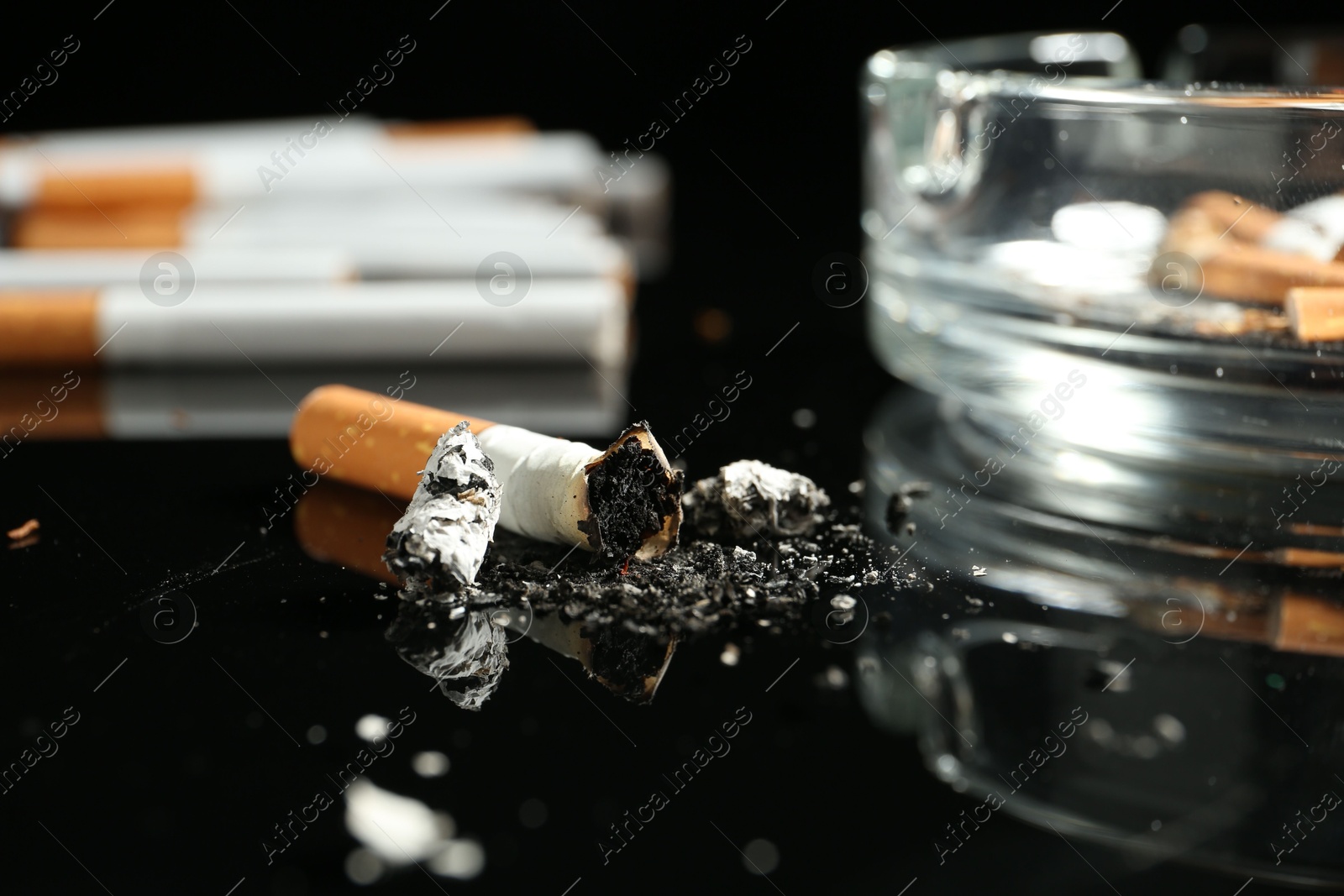 Cigarette butts and ashtray on black background, closeup Photo of Cigarette butts and ashtray on black background, closeup