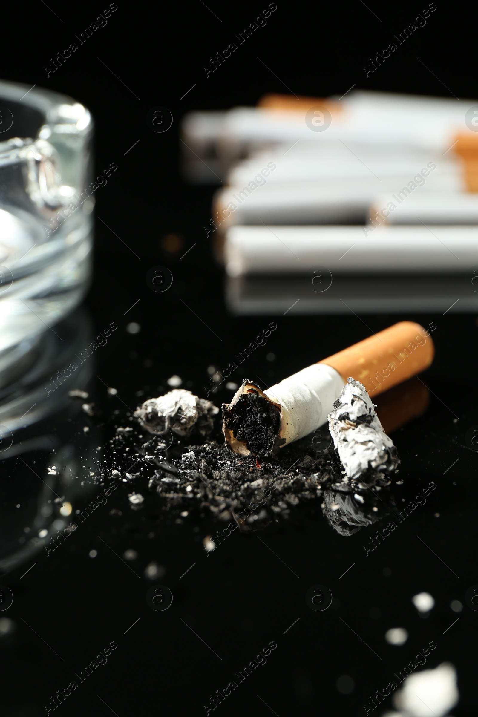 Cigarette butts and ashtray on black background, closeup Photo of Cigarette butts and ashtray on black background, closeup