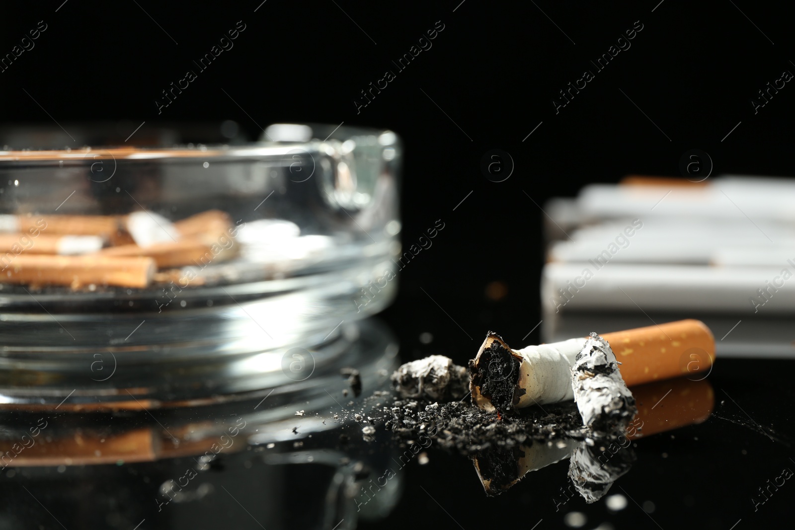 Cigarette butts and ashtray on black background, closeup Photo of Cigarette butts and ashtray on black background, closeup
