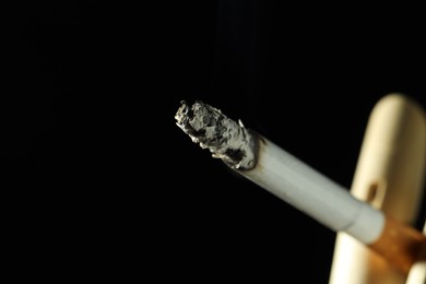 Photo of Wooden hand figure with burning cigarette on black background, closeup. Space for text