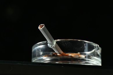 Photo of Cigarette butts in ashtray on black background, closeup