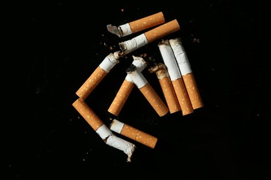 Photo of Cigarette butts with ash on black background, flat lay