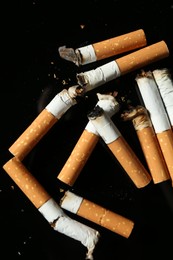 Photo of Cigarette butts with ash on black background, closeup