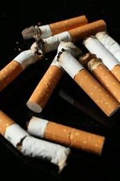 Photo of Cigarette butts with ash on black background, closeup