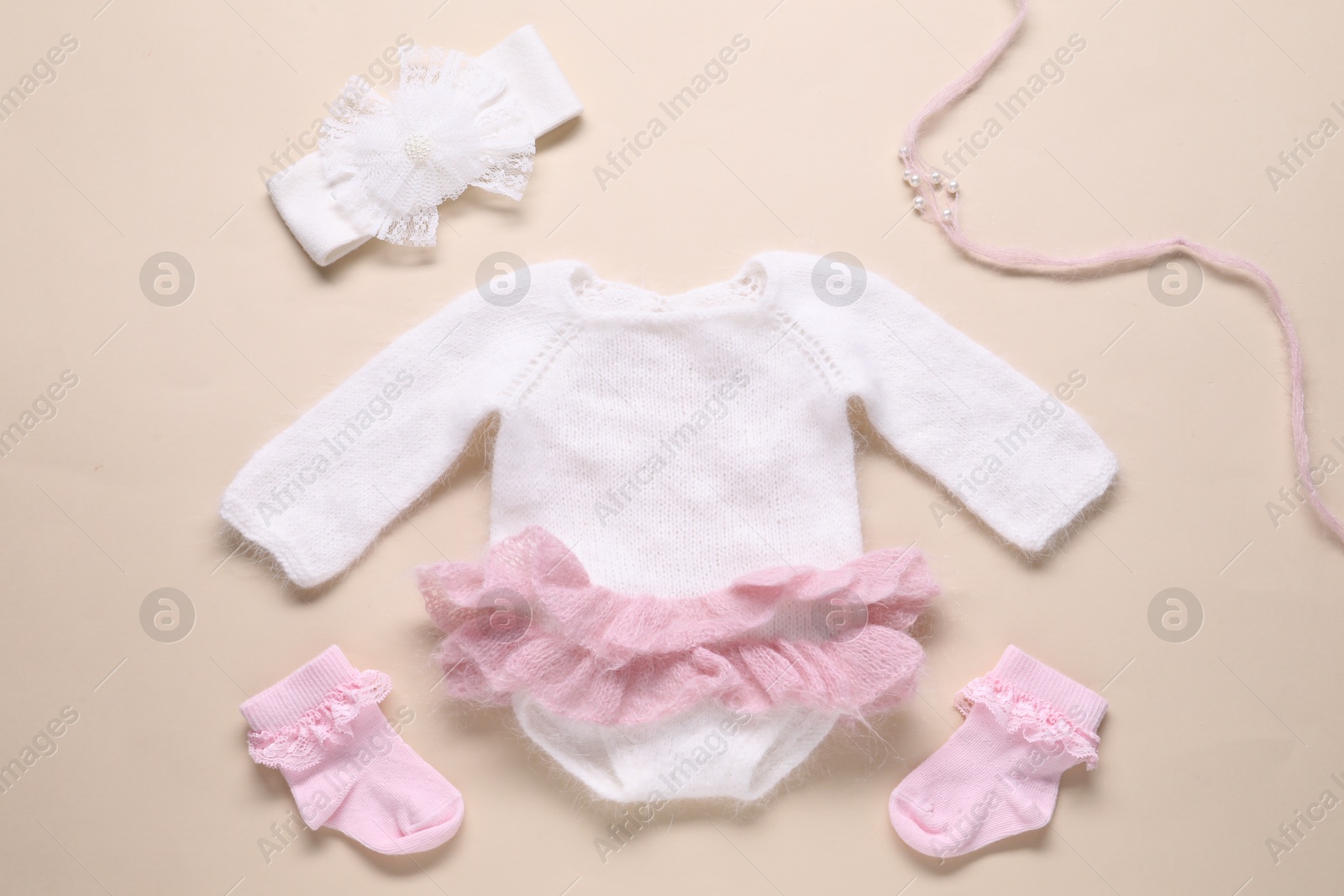 Baby clothes and accessories on beige background, flat lay Photo of Baby clothes and accessories on beige background, flat lay